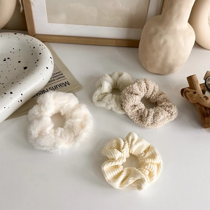 Dettaglio di 4 elastici per capelli in peluche beige crema con diverse texture