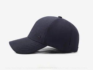 Detail showing dark blue baseball cap side with metal logo and twill fabric texture