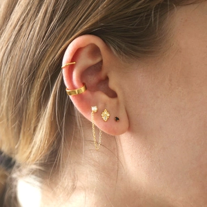 Close-up of gold ear cuff and rhinestone chain earring set on female ear lobe