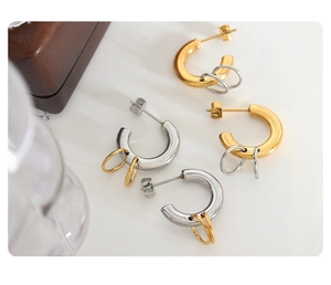 Detail of minimalist gold and silver C-shaped hoop earrings with dangling metal rings
