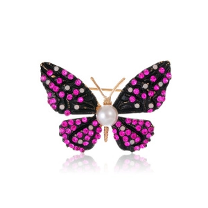 Macro detail of butterfly brooch with rose red rhinestones, white pearls and gold metal