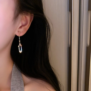 Close-up of elegant gold tassel earrings with rhinestone rectangles worn by a model