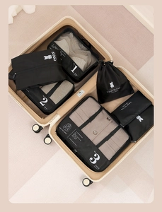 Detail view of 7-piece black travel organizers neatly packed inside a beige suitcase