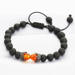 Detail of adjustable black lava stone bead bracelet with orange crown accents