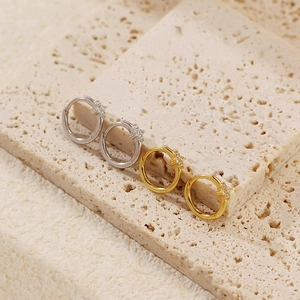 Macro detail of gold and silver clover hoop earrings with star-shaped zircons