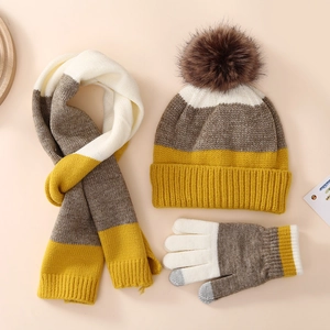 Detailed flat lay of winter knitted set with pompom hat scarf and touchscreen gloves
