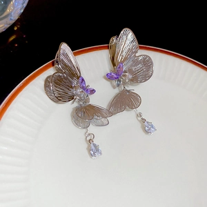 Detail of silver butterfly tassel earrings with purple wings and teardrop crystal pendants