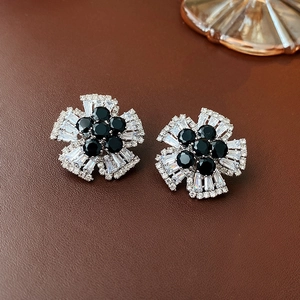Macro detail of silver flower stud earrings with black center gem and white zircon petals