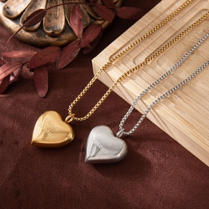 Detailed view of gold and silver heart necklaces with Mon Amour engraving on wood background