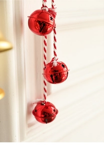 Close-up of three red metal Christmas bells with star cutouts on red and white ropes