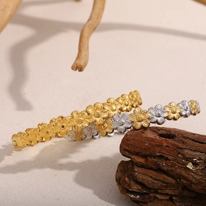 Nahaufnahme des zweifarbigen Gänseblümchen-Armreifs aus 18K Gold und Silber auf Holzgrund
