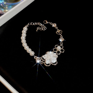 Detail of pearl bracelet with white flower charm and sparkling rhinestones on silver chain