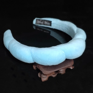 Detail of light blue braided velvet headband showing the handmade label and plush texture