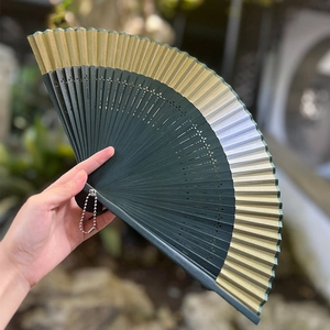 Gradient Chinese folding fan with bamboo frame and silk tassel in natural garden setting