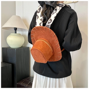 Detail of brown cowboy hat backpack featuring stylish cow print straps and suede texture