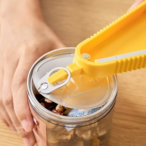 Multifunctional yellow jar opener tool for unscrewing lids on a wooden background