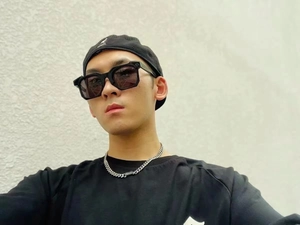 Detail view of thick black square sunglasses paired with a silver Cuban link chain necklace