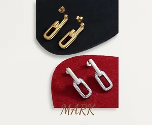 Close-up of geometric U-shaped gold and silver chain link earrings with textured finish