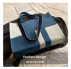 Detail of blue and beige patchwork denim tote bag with wide strap and top handles