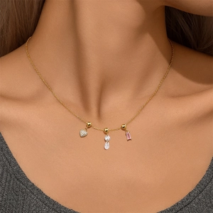 Detail of gold necklace featuring heart and emerald cut pink gemstone charms