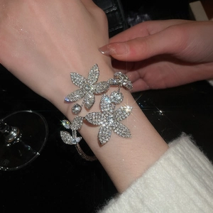 Macro shot of silver-tone floral open bangle with sparkling crystals on a model's wrist