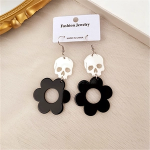 Detail shot of white skull and black flower earrings on a fashion jewelry display card