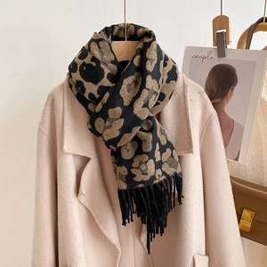 Detailed close-up of leopard print cashmere scarf with tassels styled on a model