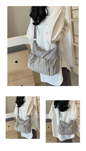 Back view of a large grey nylon crossbody bag with drawstring side pockets and wide strap