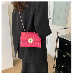 Detailed view of pink quilted handbag with gold chain strap worn over a black blazer