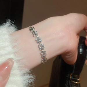 Detailed close-up of a silver zircon flower bracelet worn with an elegant white sleeve