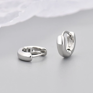 Close-up of high-polished silver huggie hoop earrings with a secure hinge closure
