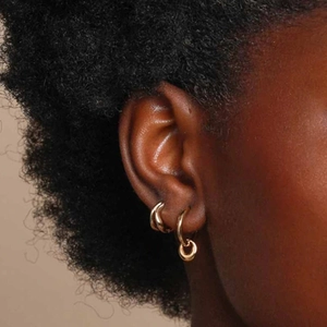 Macro shot of gold-plated hoop earrings showing tiered styling on the earlobe