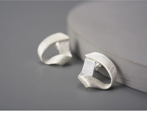 Close-up of twisted S925 sterling silver triangle earrings with a brushed metal texture