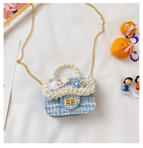 Detail of tweed kids handbag featuring a faux pearl handle and a cute plush rabbit doll