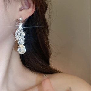 Close-up of sparkling silver teardrop rhinestone earring on model for elegant styling