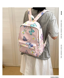 Close-up of pink backpack with butterfly and daisy prints worn by a model