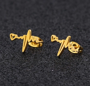 Macro shot of gold-plated script name earrings on a textured black background