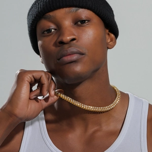 Detail of a luxury gold-plated double-row tennis chain necklace worn by a male model