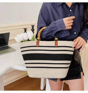 Close-up of woven tote bag featuring black and white stripes and natural bamboo handles