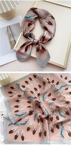 Détail d'un carré de soie rose avec des motifs de plumes marron et bleu élégants