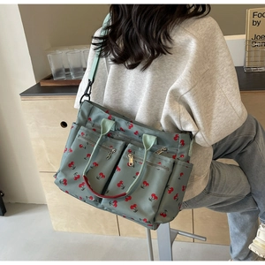 Detail of green nylon tote bag with cherry print showing large capacity and adjustable strap