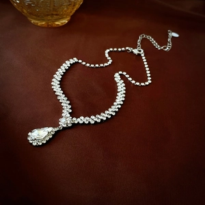 Close-up of a silver tassel necklace set with sparkling rhinestones and drop pendant