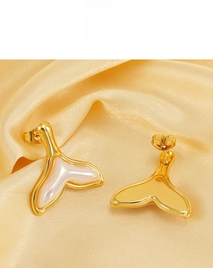 Macro shot of 18K gold plated fishtail earrings with iridescent resin on golden silk