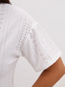 Detailed view of white cotton fabric with elegant eyelet floral embroidery and cutouts