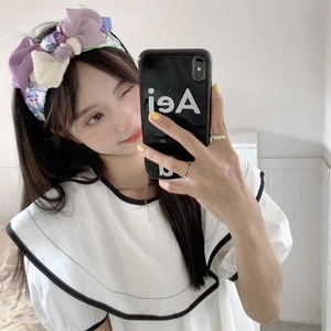 Detail van bloemrijke paarse organza haarband met dubbele strik bij een model