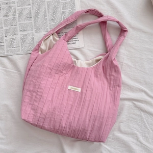 Pink pleated fabric tote bag with brand label on casual white background scene