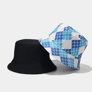 Detail view of cotton bucket hats in solid black and blue fish scale pattern print