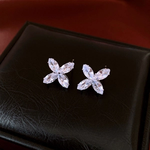 Close-up of silver clover stud earrings with white marquise stones on black leather