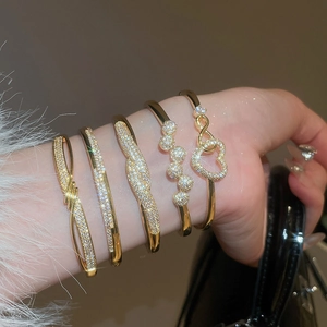 Gros plan de bracelets plaqués or 18K avec zircons et fermoirs géométriques de luxe