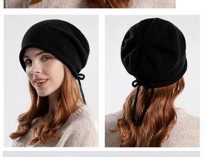 Detail view showing black knitted beanie with rear drawstring knot and soft texture
